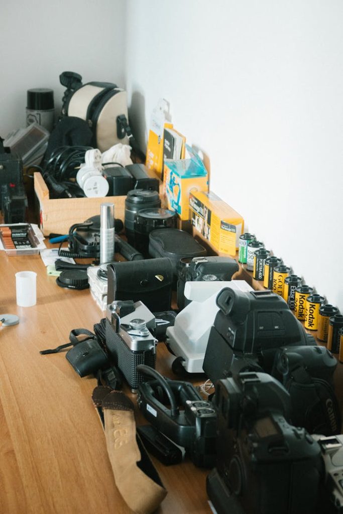 A collection of vintage and modern photography equipment laid out on a wooden table